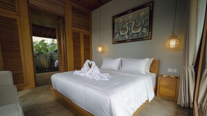 A bedroom with a large bed, wooden headboard, a painting of swans, and a hanging light fixture. - D TEBA Villas (Badung)