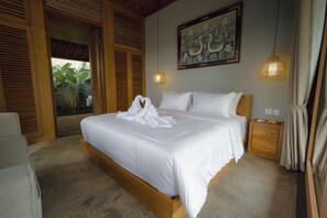Une chambre à coucher avec un grand lit, une tête de lit en bois, un tableau représentant des cygnes et un luminaire suspendu.