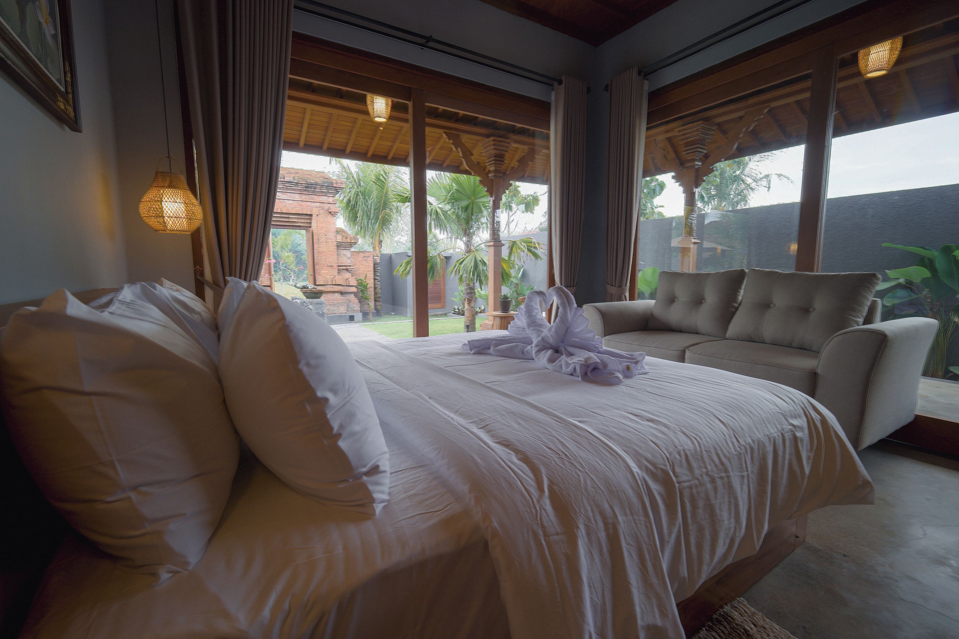 A hotel room with a bed, a sofa, and a view of the outdoors.