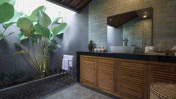 Un baño moderno con un espejo grande, un lavamanos blanco y un mueble de madera.
