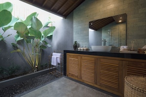 Un baño moderno con un espejo grande, un lavamanos blanco y un mueble de madera.