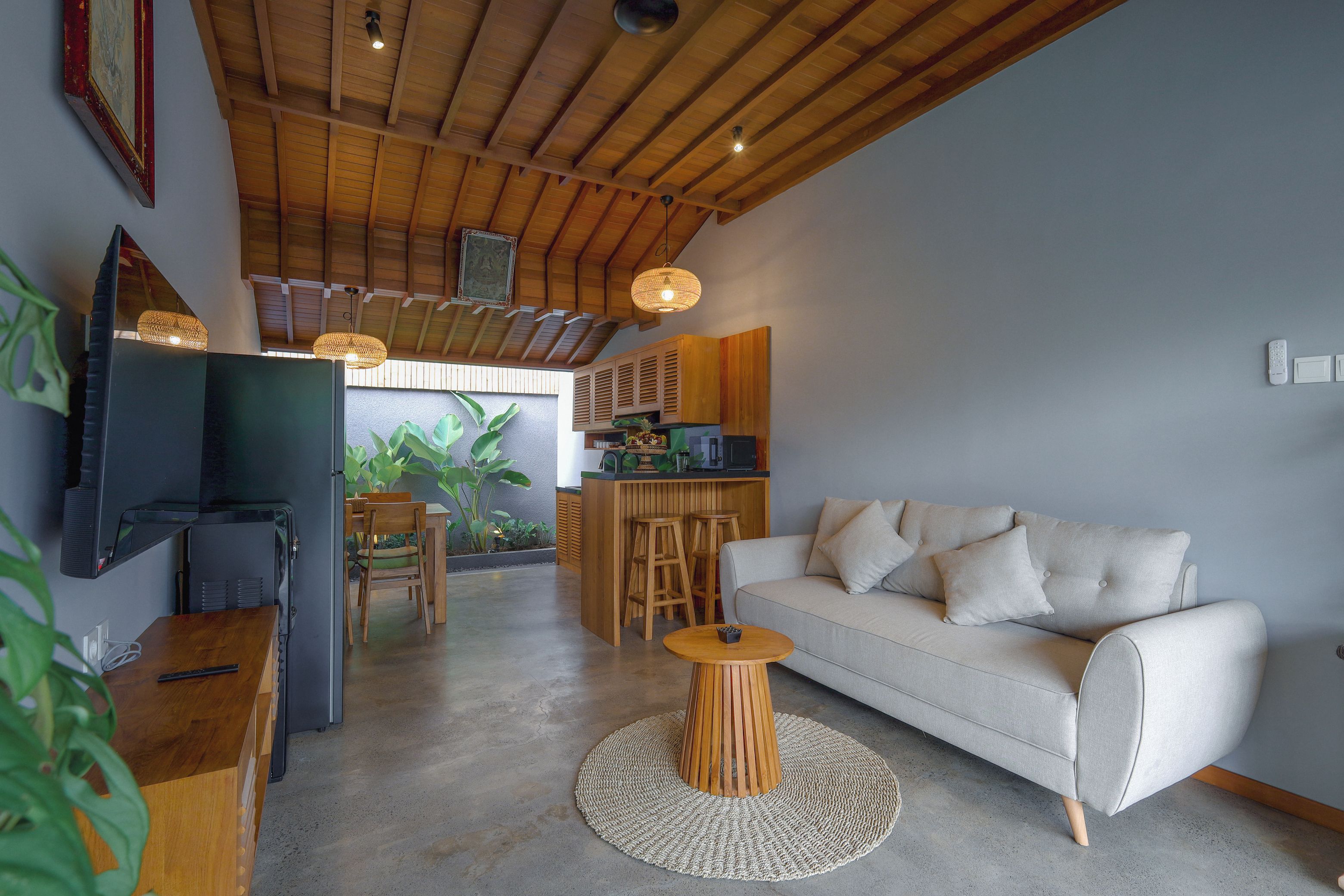 Ein modernes Wohnzimmer mit Sofa, Fernseher und einer Küchenzeile im Hintergrund.