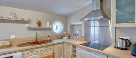 A modern kitchen with a stainless steel range hood, wooden cabinets, and a round window.