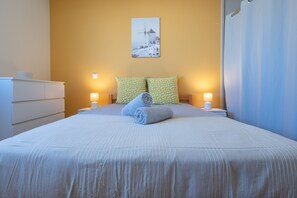 A neatly made bed with a patterned pillow, a bedside lamp, and a wall-mounted picture. - L’Écrin de l’Estuaire - 1km de la Plage (Meschers-sur-Gironde)