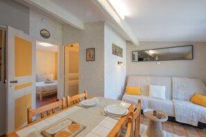 Et spiseområde med et bord dækket til to personer, en sofa med puder og et spejl på væggen.