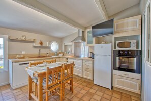 A compact kitchen with a dining area, equipped with a refrigerator, microwave, stove, and a sink. - L’Écrin de l’Estuaire - 1km de la Plage (Meschers-sur-Gironde)