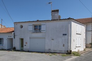 A white building with a garage door, a small window, and a chimney. - L’Écrin de l’Estuaire - 1km de la Plage (Meschers-sur-Gironde)