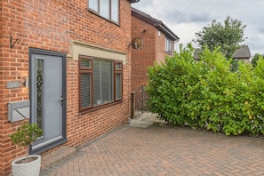 A brick house with a grey door, a window with shutters, and a hedge in the foreground. - Maison Modern - Family-Friendly with Lovely Garden - Pass the Keys (Leeds)