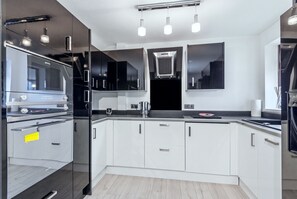 A modern kitchen with stainless steel appliances, white cabinetry, and a black countertop. - Maison Modern - Family-Friendly with Lovely Garden - Pass the Keys (Leeds)