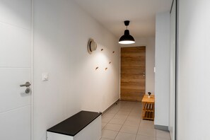 Un passadís amb una banca, una porta de fusta i una taula petita amb una planta en test.