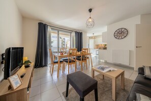 A modern living room with a dining area, a television, and a kitchen in the background. - La Citadelle - à 500 m de la télécabine du Prorel (Briancon)