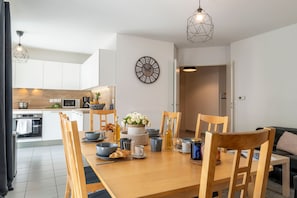 A modern kitchen with white cabinets, a wooden countertop, and a dining area with a wooden table and chairs. - La Citadelle - à 500 m de la télécabine du Prorel (Briancon)