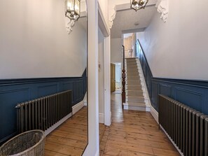 A hallway with a staircase, wooden floors, and a radiator. - The Seaside Family Retreat - Pass the Keys (Whitley Bay)