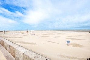 A beach with a concrete barrier, a sign reading 'BERCK SUR MER', and a distant view of the sea. - Le Studio des Oyats - à 400 m de la plage (Berck)
