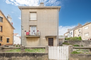 A two-story building with a balcony, a door, and a small garden area. - Le Studio des Oyats - à 400 m de la plage (Berck)