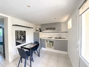 A modern kitchen with grey cabinets, a black countertop, and a tiled backsplash.