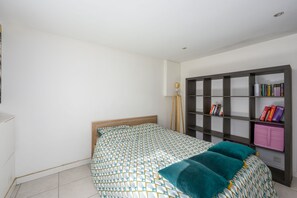A bedroom with a bed, a bookshelf, and a bedside lamp.