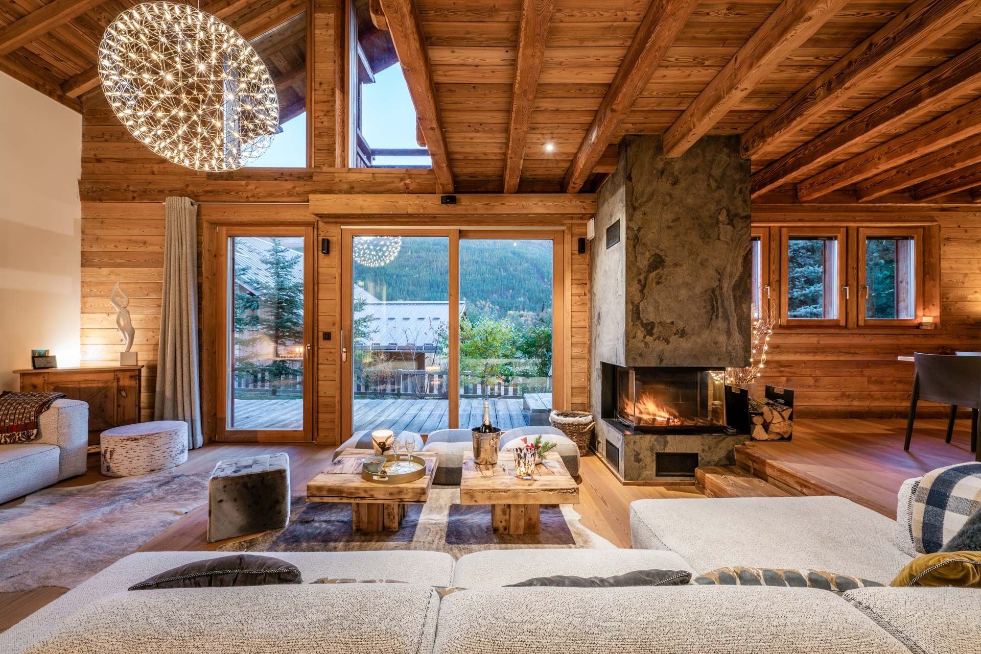 A cozy cabin interior with a fireplace, wooden walls, and a large window overlooking a snowy landscape.