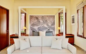 Ein modernes Wohnzimmer mit einer großen Couch, zwei Beistelltischen und einer Wandmalerei.