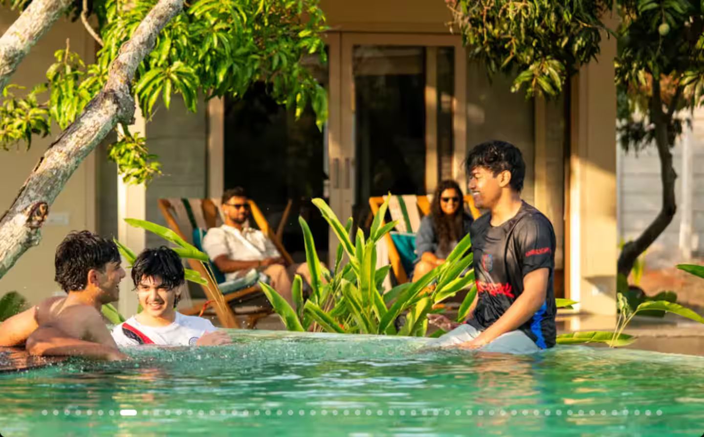 A pool area with people relaxing and a building in the background.