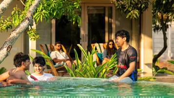 A pool area with people relaxing and a building in the background.