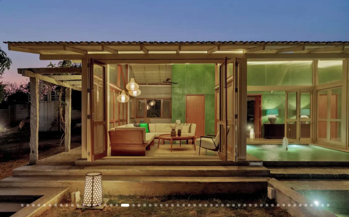 Ein modernes Haus mit Glasfassade, einem Pool und einer Terrasse mit Möbeln.