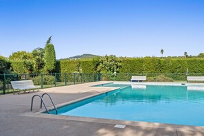 A swimming pool with a green fence, two benches, and a clear sky. - Le Panoramic Lérins - 2km de la Plage (Antibes)