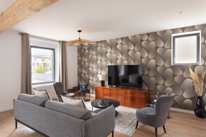 Ein modernes Wohnzimmer mit einem grauen Sofa, einem Fernseher und einer Wand mit Muster.