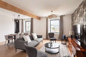 A modern living room with a sofa, armchairs, a coffee table, and a dining area with a table and chairs. - Maison Nova - charmant appt avec parking privé (Rennes)