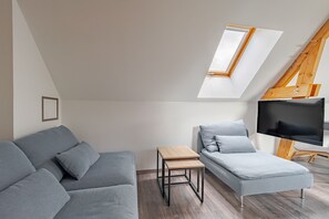 A modern living room with a loft bed, a small table, a sofa, and a television.