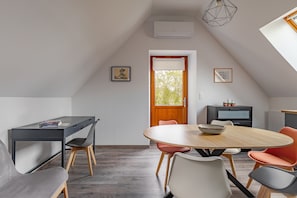 A modern, well-lit dining area with a round table, chairs, and a television. - La Saulnerie - appt climatisé avec jardin (Martizay)