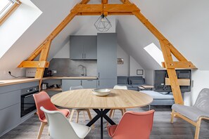A modern loft with a kitchen, dining area, and seating space. - La Saulnerie - appt climatisé avec jardin (Martizay)