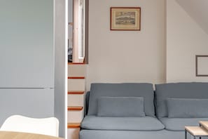 A compact living space with a sofa, a small table, and a framed picture on the wall. - La Saulnerie - appt climatisé avec jardin (Martizay)