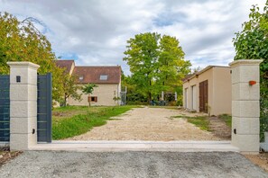 A gravel driveway leading to a building with a tiled roof and a stone wall. - La Saulnerie - appt climatisé avec jardin (Martizay)