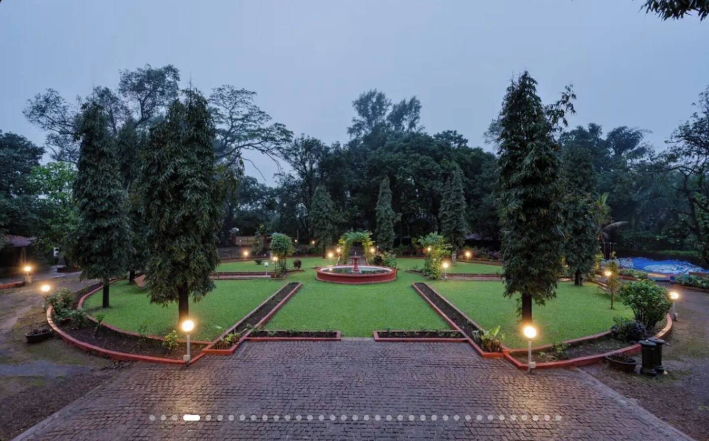 A landscaped garden with a central fountain, surrounded by pathways and trees.