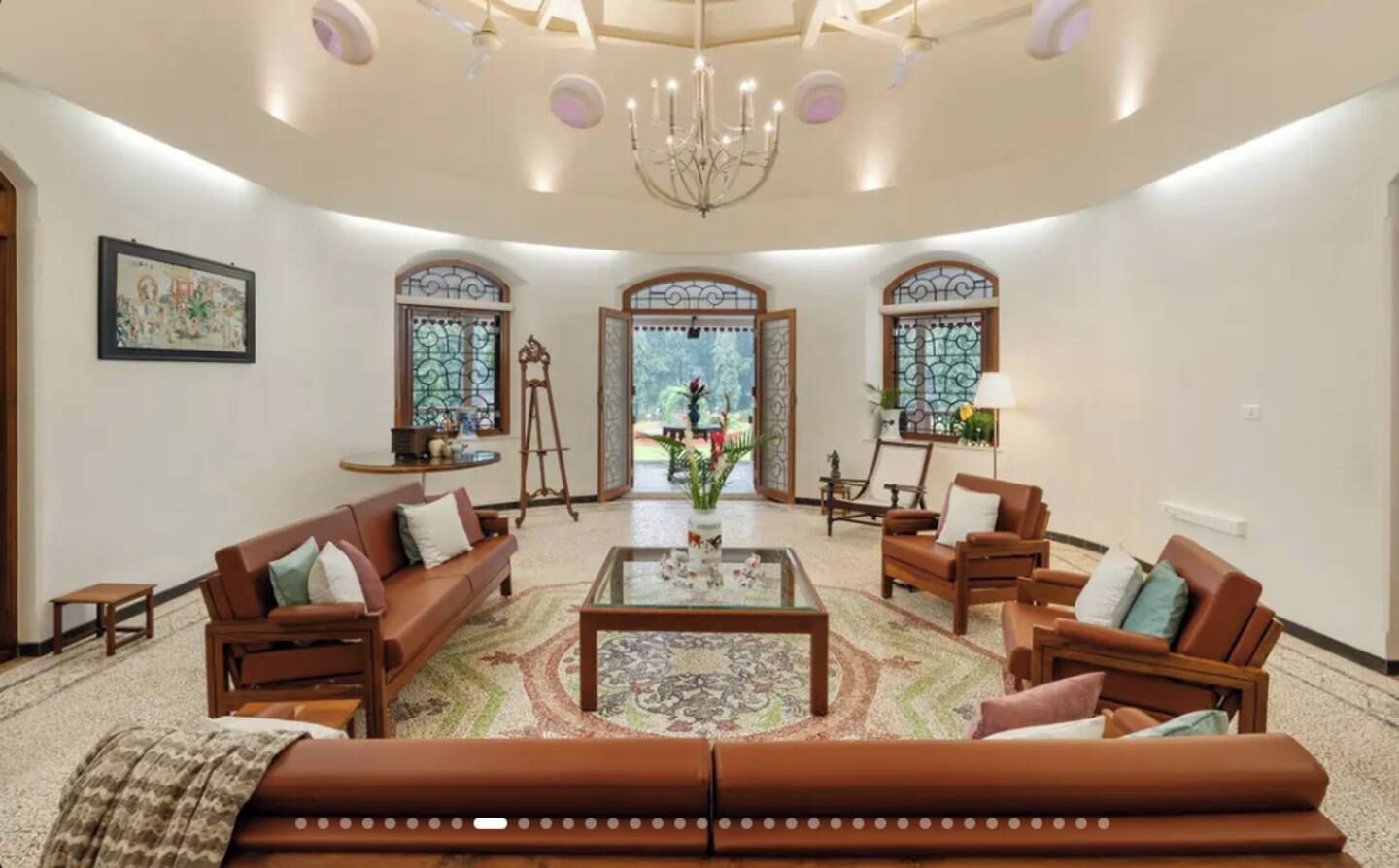 A spacious living room with a large sofa, armchairs, a coffee table, and a chandelier.