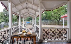 Un'area pranzo all'aperto riparata, con un tavolo imbandito per due, sedie e vista sul verde circostante.