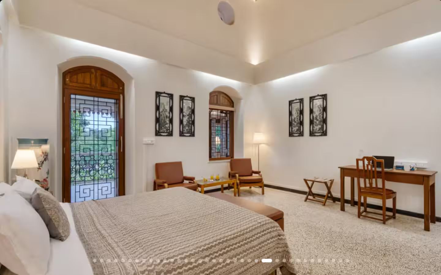 Una camera d'albergo con un letto, due sedie, una scrivania e un tavolino.