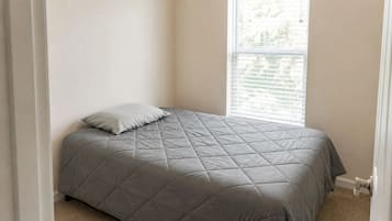 Un dormitorio con una cama, una ventana con persianas y una puerta.