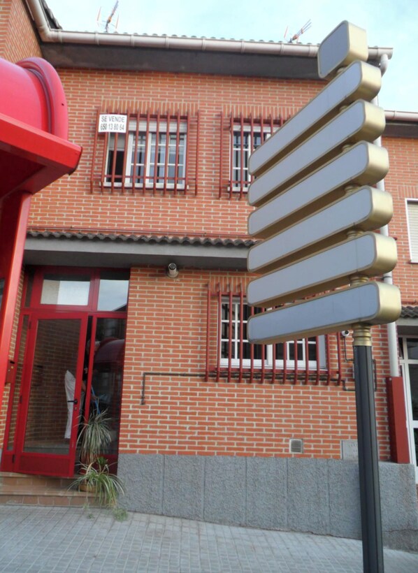 A red brick building with a signboard, a red door, and a potted plant. - Bright house with good transportation access (Algete)