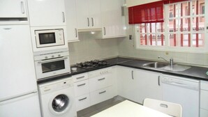 Una cucina compatta con lavatrice, fornello, forno a microonde e lavandino.