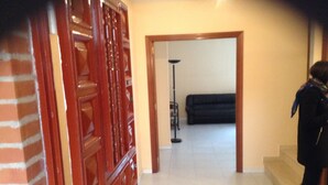 A hallway with a wooden door, a black sofa, and a floor lamp. - Bright house with good transportation access (Algete)