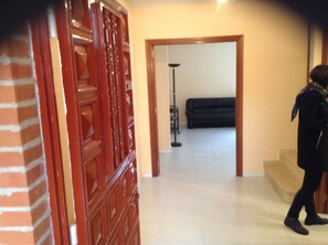 A hallway with a wooden door, a black sofa, and a floor lamp. - Bright house with good transportation access (Algete)
