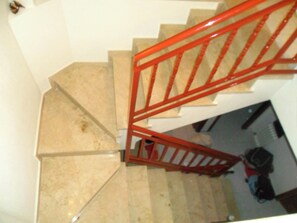 A staircase with beige steps and a red handrail.
