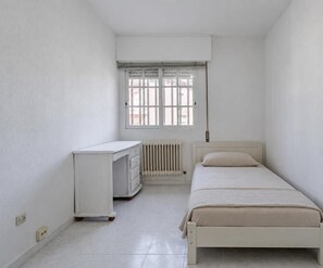 A bedroom with a bed, a desk, and a radiator. - Bright house with good transportation access (Algete)
