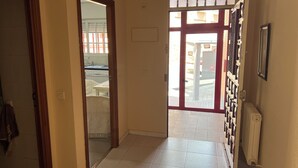 A hallway with a tiled floor, a door leading to a kitchen area, and a radiator on the wall. - Bright house with good transportation access (Algete)