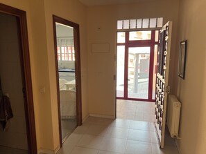 A hallway with a tiled floor, a door leading to a kitchen area, and a radiator on the wall. - Bright house with good transportation access (Algete)