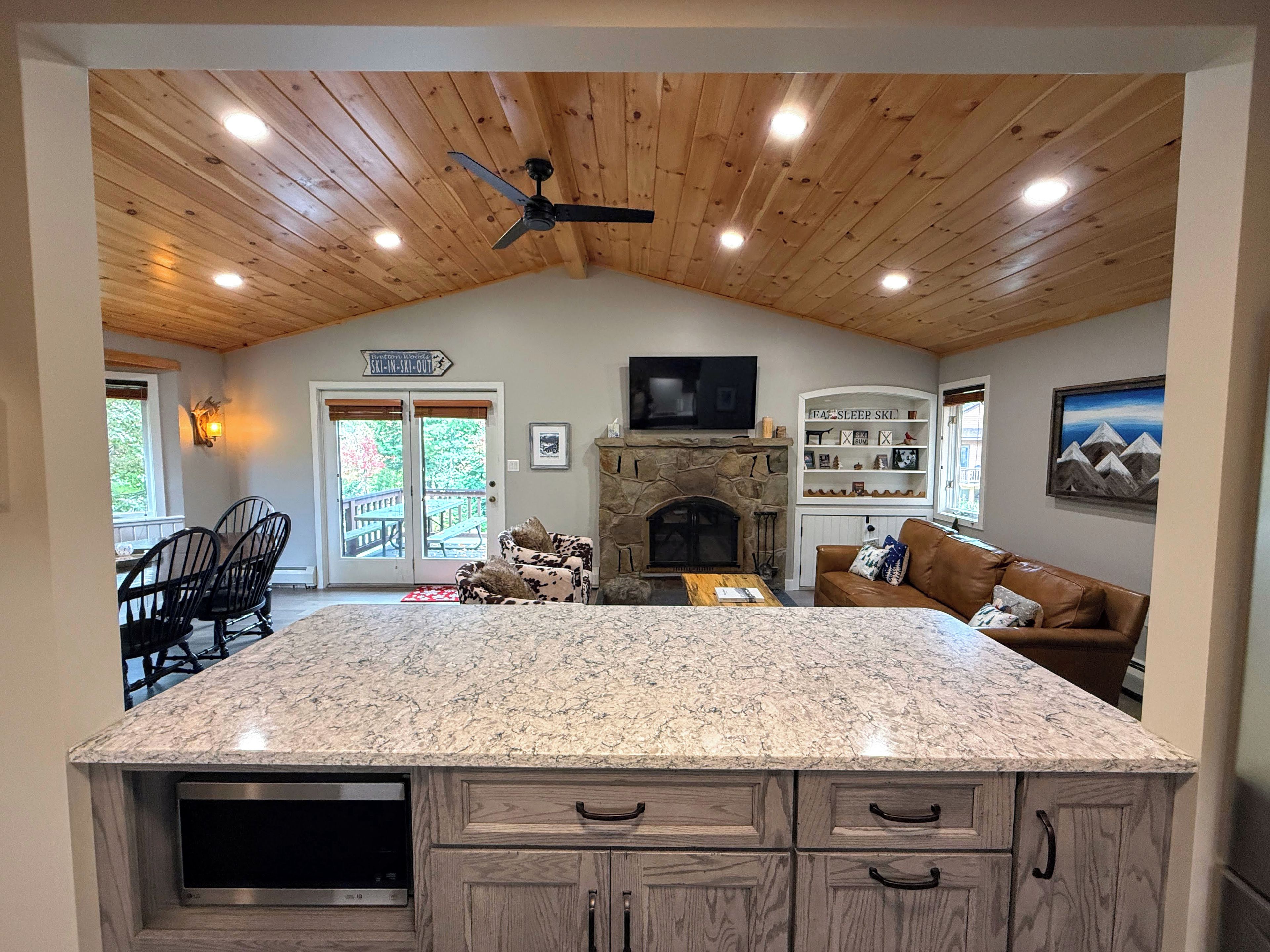 A spacious kitchen with a granite countertop, wooden cabinets, and a stone fireplace.