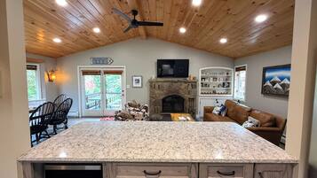 A spacious kitchen with a granite countertop, wooden cabinets, and a stone fireplace.