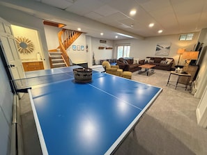 Un saló amb una taula de ping-pong, una escala i un sofà.